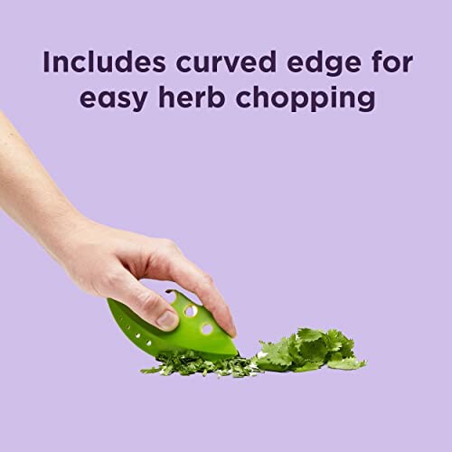 Hand using a green tool to chop herbs on a purple background.